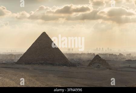 La pyramide de Mykerinos, la plus petite des trois pyramides principales de Gizeh au Caire en Égypte. À l'arrière-plan, des gratte-ciel du Caire. *** La pyramide de Mykerinos, la plus petite des trois pyramides principales de Gizeh au Caire, en Égypte. À l'arrière-plan se dressent des gratte-ciel du Caire. Banque D'Images