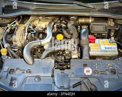 Vue avant du compartiment moteur ouvert d'une Renault Clio RS noire montrant le moteur turbocompressé, la batterie Varta AGM et l'emblème Renault Sport sur la calandre Banque D'Images