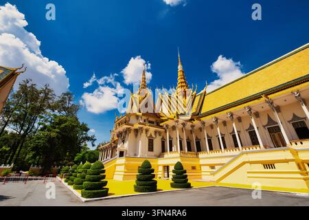 Vue du Palais royal du Cambodge présentant des toits jaunes ornés et des topiaires bien entretenues sous un ciel bleu éclatant à Phnom Penh, Phnom Penh, Cambodge. Banque D'Images