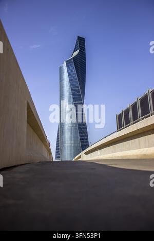 Tour en verre bleu torsadée s'élevant au-delà des murs d'une rampe en béton, vue en contre-plongée sous un ciel bleu, Kuwait City, Koweït Banque D'Images