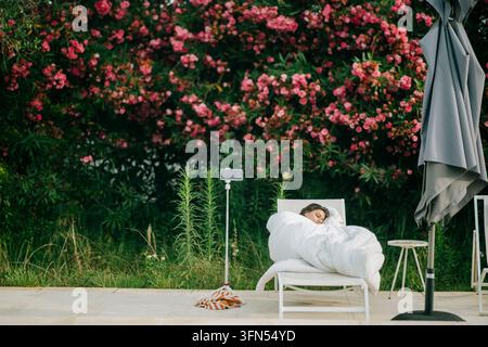 Femme alanguie en robe blanche sur une chaise longue Banque D'Images
