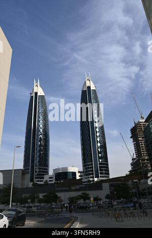 Une prise de vue en contre-plongé capture deux gratte-ciel modernes et imposants reflétés dans un ciel bleu clair. Les bâtiments sont situés sur une rue urbaine avec une construction Banque D'Images