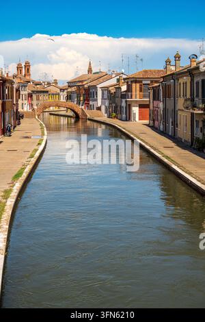 Un plan vertical du canal principal de Comacchio qui coule paisiblement entre des rangées de bâtiments historiques colorés. À l'arrière-plan se dresse le célèbre bri Banque D'Images