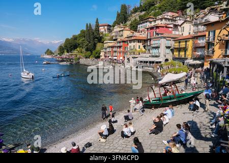 Varenna, Italie – 5 avril 2026 : côte du lac de Côme en Italie avec des touristes, des bateaux et une foule rassemblée le long du front de mer coloré du village de Varenna Banque D'Images
