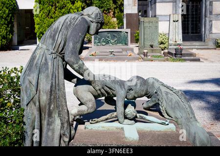 Sculpture funéraire en bronze représentant une femme et des enfants autour d'une croix sur la tombe Cimitero Monumentale di Milano Cimetière monumental de Milan Italie Banque D'Images