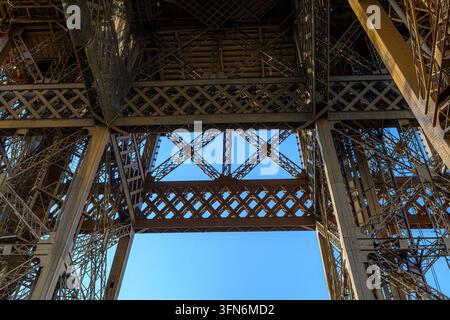 Les cadres en treillis de fer s'élèvent contre un ciel bleu clair. Les poutres structurelles forment des motifs géométriques complexes. La vue par le bas révèle une échelle architecturale grandiose Banque D'Images