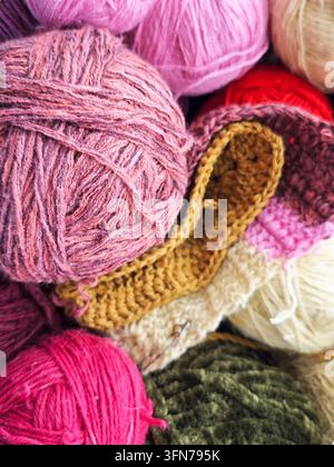 Des boules de laine de différentes couleurs sont empilées ensemble, montrant la texture et la chaleur pour les projets de tricot et de bricolage. Banque D'Images
