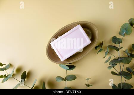 Savon rose dans un porte-savon marron isolé sur un fond beige. Barre de savon sur un support en plastique pour la salle de bain et la douche. Banque D'Images