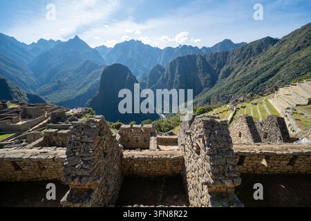 Une vue panoramique de Machu Picchu au Pérou montrant les ruines en pierre anciennes des Incas, l'agriculture en terrasses et les montagnes dramatiques des Andes sous un ciel lumineux, évoquant Banque D'Images