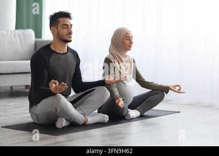 S'attendre à ce que les conjoints musulmans pratiquent le yoga ensemble à la maison, assis dans la pose de Lotus Banque D'Images