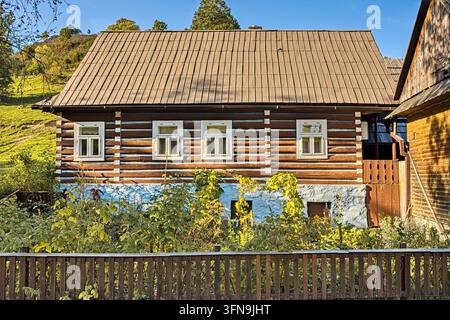Vue avant d'une cabane en rondins traditionnelle avec une base blanche et des fenêtres dans la réserve du patrimoine d'Osturňa, Slovaquie. Banque D'Images
