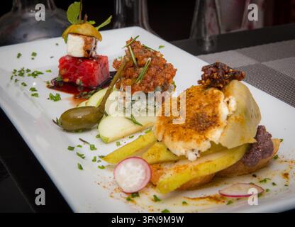 Une photographie en gros plan mettant en valeur un trio élégant de hors-d'œuvre gastronomiques, mettant l'accent sur un crostini assaisonné de poire et de chèvre servi sur un long wh Banque D'Images
