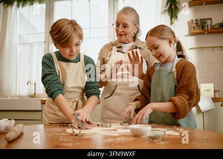 Sénior avec petits-enfants cuisinant des biscuits dans la cuisine Banque D'Images