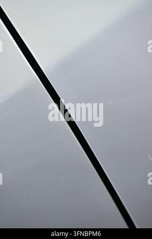 Photographie macro détaillée horizontale mettant l'accent sur une couture de panneau horizontale propre à travers une surface métallique peinte en blanc lisse et brillante avec un éclairage doux Banque D'Images