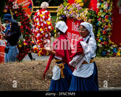 Participants vêtus de tenues traditionnelles colombiennes et de costumes fleuris festifs marchant dans la rue pendant la Feria de las Flores, à Medellín. Banque D'Images