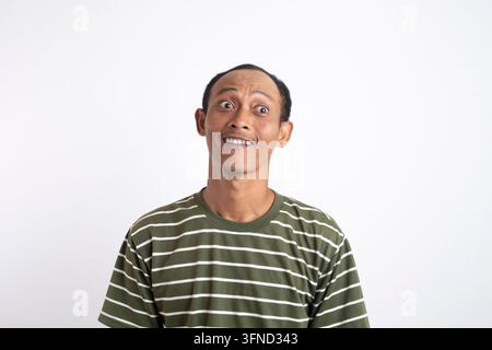 Portrait d'un jeune homme barbu à la peau foncée, ravi, regardant la caméra avec les yeux grands ouverts et tenant la main sur son ventre tout en riant joyeusement, Banque D'Images