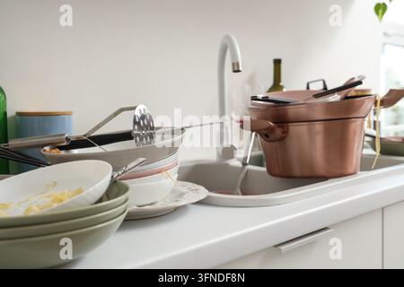 Ménages domestiques et épuisement professionnel domestique, pile de vaisselle sale et évier de cuisine en désordre après une soirée dans un intérieur moderne Banque D'Images