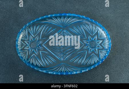 Assiette vide vintage en verre cristal taillé bleu ovale plateau vue par le dessus sur une table à fond noir Banque D'Images