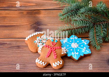 Homme en pain d'épices et biscuits en forme de flocon de neige sur une table en bois avec branche de pin, gros plan Banque D'Images