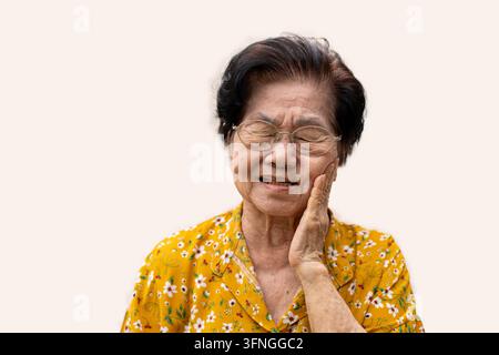 Ancienne femme asiatique souffrant d'une forte douleur dentaire, tenant sa joue et souffrant d'une forte douleur dentaire sur fond blanc, carie, sensibilité dentaire Banque D'Images