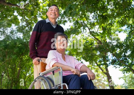 Les couples âgés ou les aidants prennent soin du patient en fauteuil roulant. Concept d'un retraite heureuse avec des soins d'un aidant et des économies et des seniors Banque D'Images