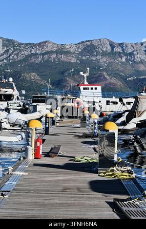 Photographie de stock macro verticale détaillée montrant un ponton de marina en bois avec des yachts, des équipements de sécurité et des cordes à l'extérieur sous la lumière naturelle du jour. Banque D'Images