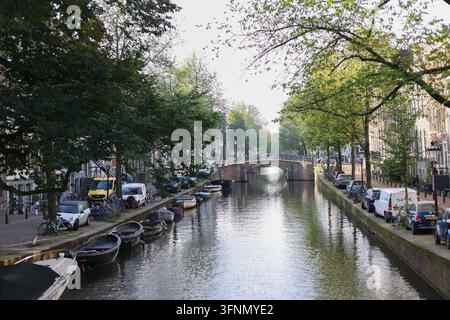 Amsterdam, Pays-Bas – 2 octobre 2026 : Canal pittoresque avec des bateaux amarrés, des vélos et un petit pont dans le centre historique de la ville. Banque D'Images