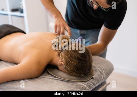 Physiothérapeute effectuant une acupuncture sèche sur le dos d'une patiente Banque D'Images
