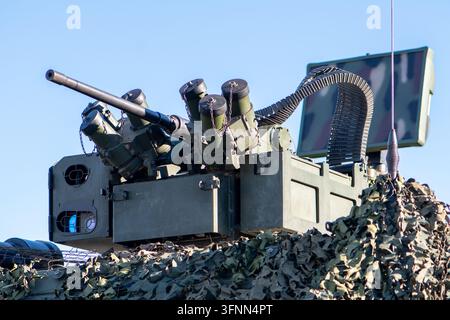 VIENNE, AUTRICHE, 26 octobre 2025 : Un tourelle antiaérienne militaire avec canon, lanceurs de missiles et filet de camouflage se dresse contre un ciel bleu. Banque D'Images
