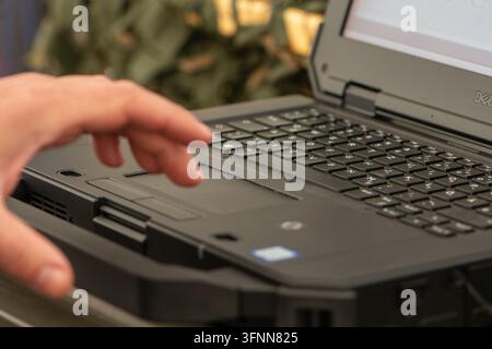 VIENNE, AUTRICHE, 26 octobre 2025 : Une main se tend vers un clavier d'ordinateur portable Dell dans une vue intérieure en gros plan. Banque D'Images