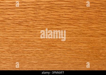 Surface en bois aux tons chauds naturels présentant un motif de veines linéaires fines et une texture lisse polie avec un éclairage doux. Banque D'Images