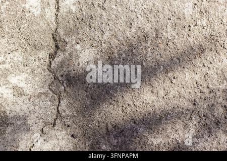 Vue aérienne d'un sol en béton rugueux avec une fissure verticale distincte et une ombre sombre et douce projetée sur la surface texturée, convenant comme arrière-plan. Photo de haute qualité Banque D'Images