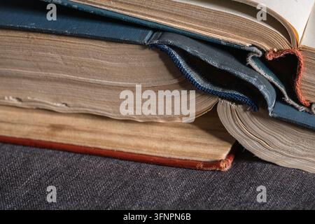 Pile de livres anciens ouverts avec des pages jaunies et des couvertures usées. Représentant la littérature, la sagesse et l'apprentissage vintage Banque D'Images