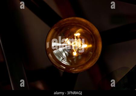 Vue rapprochée d'une ampoule Edison vintage lumineuse avec filament chaud dans un intérieur sombre Banque D'Images