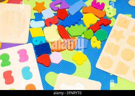Vue en contre-plongée de nombreux blocs de puzzle en bois colorés et planches éparpillés sur un tapis de jeu en mousse texturé lumineux, espace de copie Banque D'Images