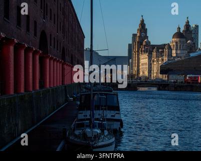Bateaux amarrés au Royal Albert Dock de Liverpool, en Angleterre, avec les Three Graces historiques et le Royal Liver Building en arrière-plan. Banque D'Images