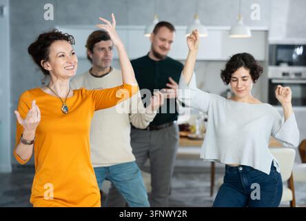 Un homme et une femme amateurs ont une sorcière, exécutent une danse en couple lors d'une fête avec des amis. Les couples s'amusent et dansent, passent du temps en bonne compagnie Banque D'Images