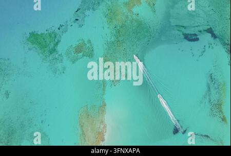 Vue aérienne de dessus d'un bateau à moteur naviguant à travers les eaux turquoise claires de la lagune de Balos, laissant un sillage d'écume blanche sur l'île de Crète en Grèce Banque D'Images
