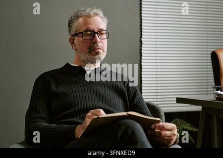 Homme d'âge moyen tenant un cahier lors d'une consultation de thérapie Banque D'Images