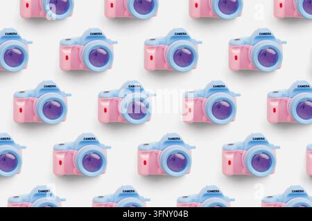 Motif sans couture mettant en scène de petites caméras jouets en rose et bleu disposées en rangées sur un fond clair. Banque D'Images