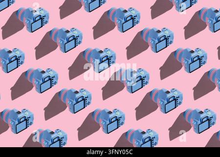 Motif répétitif isométrique mettant en scène de petites caméras-jouets disposées en diagonale avec des ombres sur un fond rose. Banque D'Images