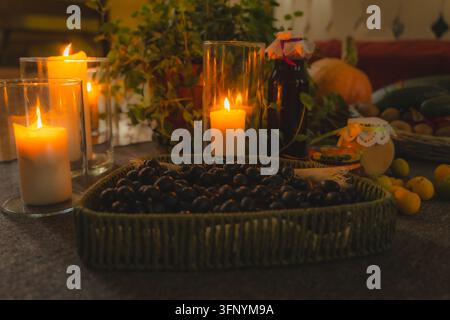 Nature morte de récolte automnale avec des baies sombres, des bougies et des conserves maison Banque D'Images