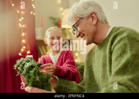 Homme senior et fille décorant le sapin de Noël à la maison Banque D'Images