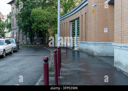 hongrie, budapest 2021 05 30 : Scène urbaine de rue mettant en scène des voitures garées, un trottoir avec des bornes et des bâtiments en brique, capturée en plein jour avec un œ Banque D'Images