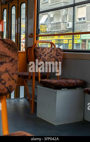 Hongrie, Budapest 2021 05 30 : Vue intérieure d’un tramway de transport public avec des sièges orange vides et des garnissages à motifs, lumière naturelle du jour, prise de vue verticale Banque D'Images