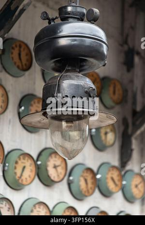 Bangkok, Thaïlande - 3 oct 2026 - Une lanterne industrielle vintage est suspendue en premier plan, suspendue contre un fond rempli d'une série de Banque D'Images