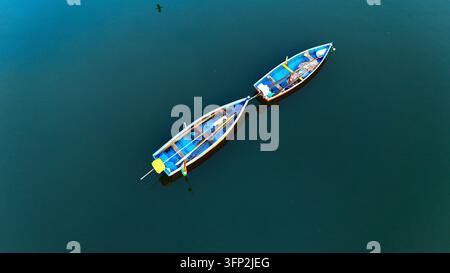 Vue aérienne de deux petits bateaux de pêche bleus flottant sur les eaux calmes et sombres de la rivière Tapi à Surat, Gujarat, en Inde. Banque D'Images