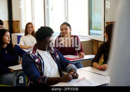 Différents étudiants engagés et concentrés pendant un cours, écoutant attentivement dans une classe lumineuse d'un lycée ou d'une université Banque D'Images
