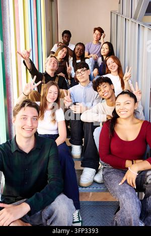 Groupe divers d'étudiants et d'amis souriants posant ensemble sur les escaliers de l'école, célébrant la jeunesse et l'éducation sur le campus Banque D'Images