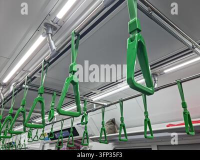 Rampes vertes suspendues à l'intérieur d'un train de transport public propre pour les passagers debout. Banque D'Images